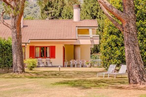 Ein Haus mit Ziegeldach, Balkon und Garten mit Stühlen und Tisch.