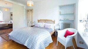 A bedroom with a bed, a chair, a shelf, and a radiator. - Villa Lesa (Lesa)