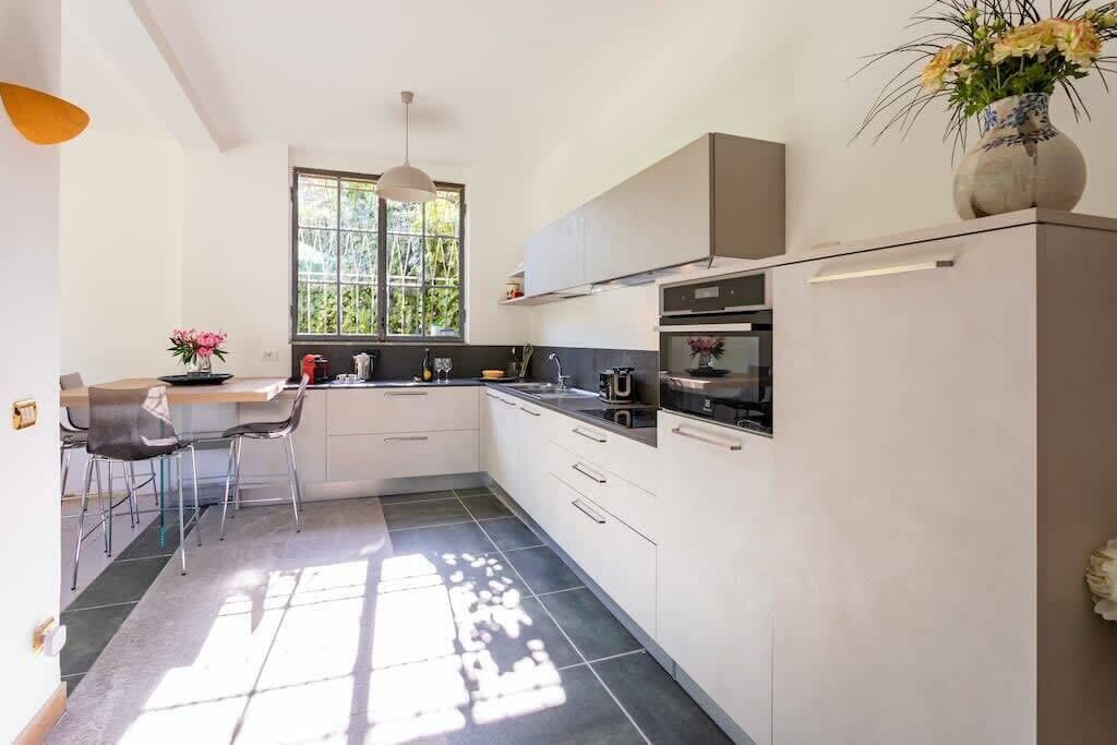 A modern kitchen with white cabinets, a dining area with a table and chairs, and a window providing natural light.