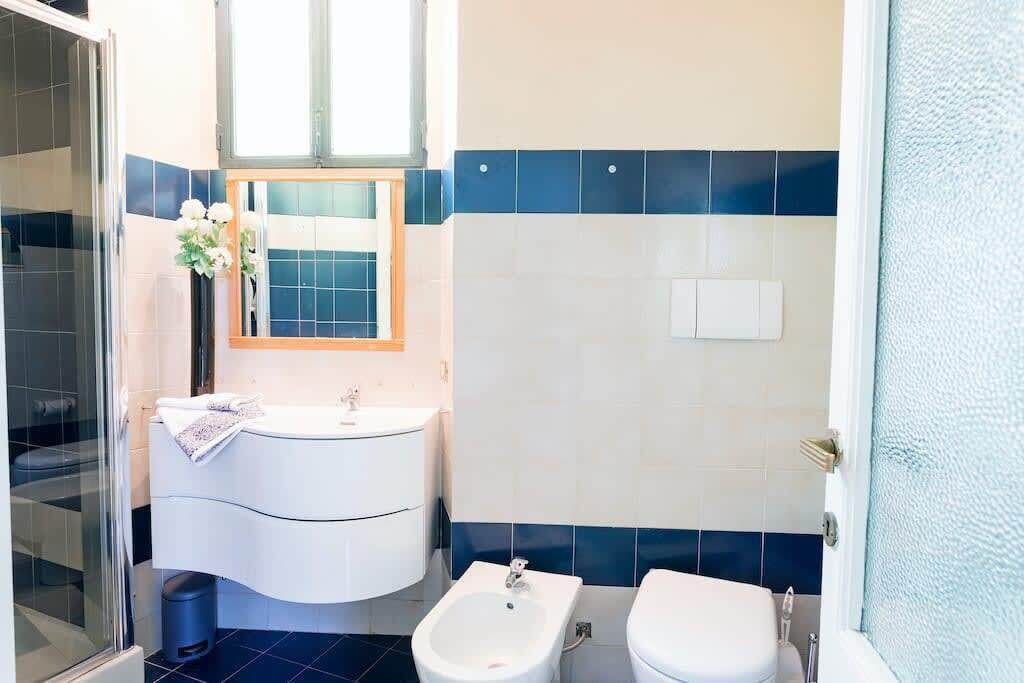 A modern bathroom with a glass shower enclosure, a white sink with a mirror, and a bidet.