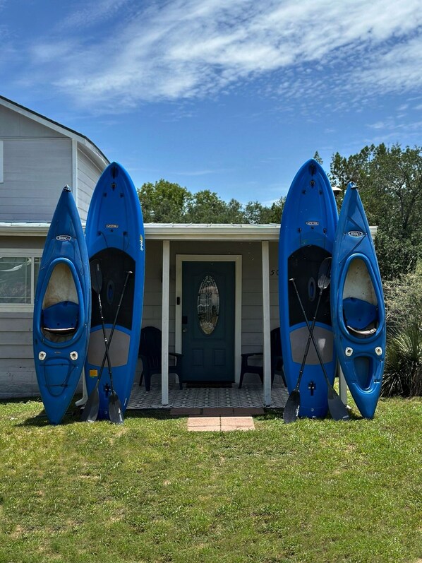 A house with a porch and three kayaks leaning against it.
