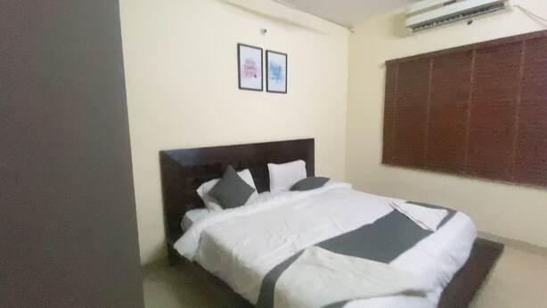 Un dormitorio con una cama, aire acondicionado de pared y dos cuadros enmarcados.