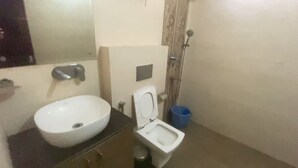 Un baño pequeño con lavamanos blanco, inodoro y ducha.