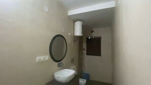 Un baño pequeño con un lavamanos blanco, un espejo, un perchero para toallas y un inodoro.
