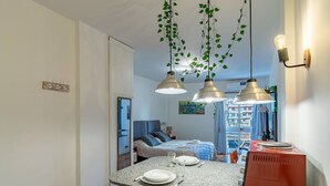 Moderni keittiö, jossa on graniittitasot, roikkuvia kasveja, riippuvalaisimia ja punainen kodinkone.
