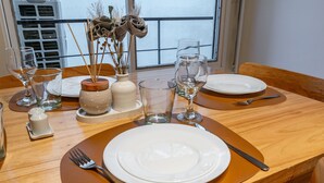 Een eettafel gedekt met borden, glazen en bestek, met een uitzicht op de omgeving.