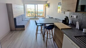 Una cocina moderna con comedor, ventanas amplias y vista al mar.