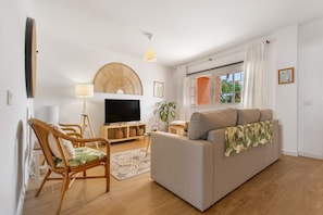 A living room with a sofa, a television, a lamp, and a plant.