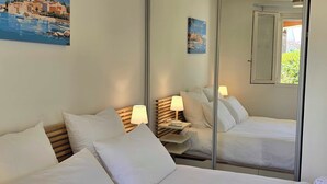 Ein Hotelzimmer mit Bett, Nachttischen, Lampen und einem großen Spiegel, der den Raum widerspiegelt.