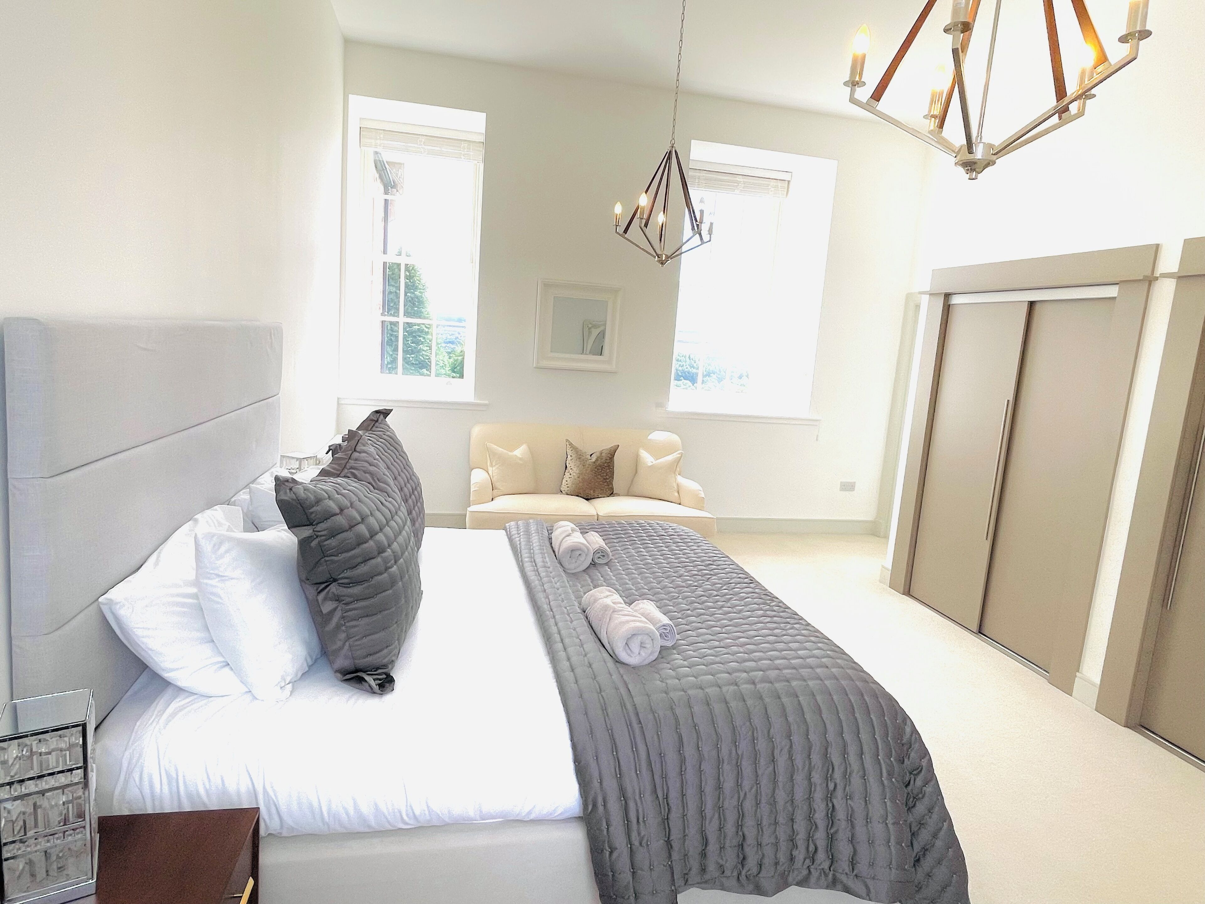 A bedroom with a bed, a bedside table, a dresser, and a window.