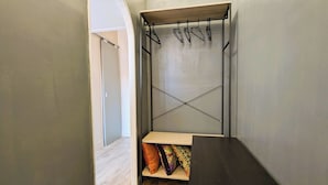 Ein schmaler Flur mit einer hölzernen Sitzbank und einem Metallgestell mit Kleiderbügeln.