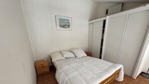 A bedroom with a bed, wooden nightstand, and a wardrobe.