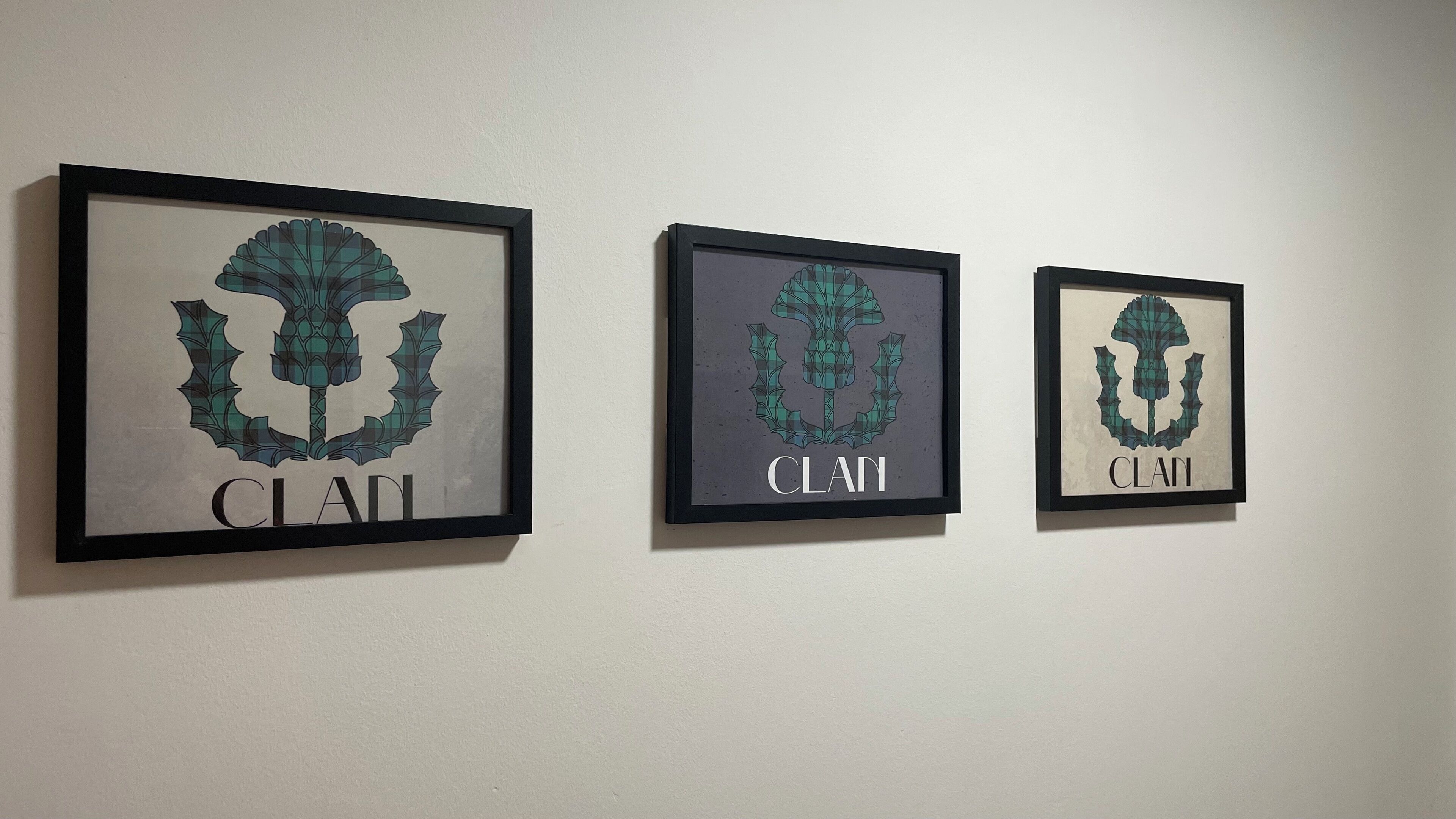 Three framed artworks with the word "CLAI" on a wall.