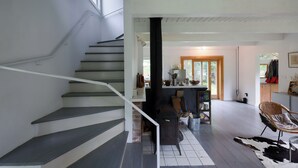 Una escalera conduce a una sala de estar con chimenea, una mesa de comedor y una silla.