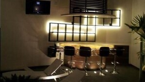 A modern interior with a dining area featuring a unique light fixture and a flat-screen TV mounted on the wall. - Hotel Teocalli Tula (Tula de Allende)