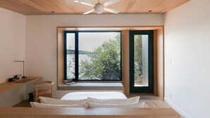 A bedroom with a large window, a bed, a desk, and a ceiling fan. - Lakeside Calm at Dimensions | Cabin One (Algonquin Highlands)