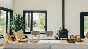 Un salon spacieux avec un haut plafond, de grandes fenêtres, une cheminée et un coin salon confortable.