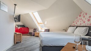 A modern bedroom with a large bed, a wooden nightstand, a red kitchen area, and a skylight. - Tranquil Retreat Near Veerse Meer (Kamperland)