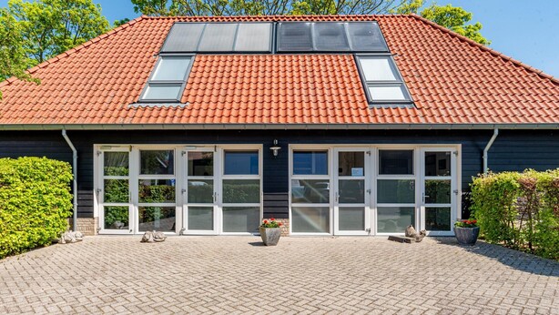 A building with a red-tiled roof, large windows, and a paved entrance area with potted plants. - Tranquil Retreat Near Veerse Meer (Kamperland)