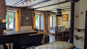 Una cocina rústica con pared de piedra, muebles de madera y un comedor con mesa y sillas.