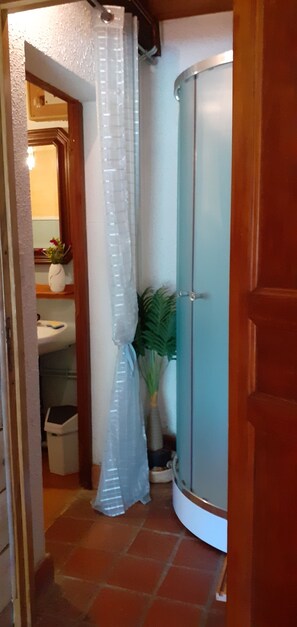 Een badkamer met een douche, toilet, wastafel en een plant.