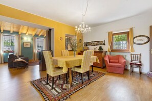 A dining area with a table set for four, a chandelier, and a patterned rug.