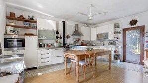 Una cocina moderna con armarios blancos, una mesa de comedor de madera y un ventilador de techo.