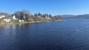 A river with a town on the opposite bank, featuring houses and a church. - Migdale Heights - Luxury Cabins in The Highlands (Ardgay)