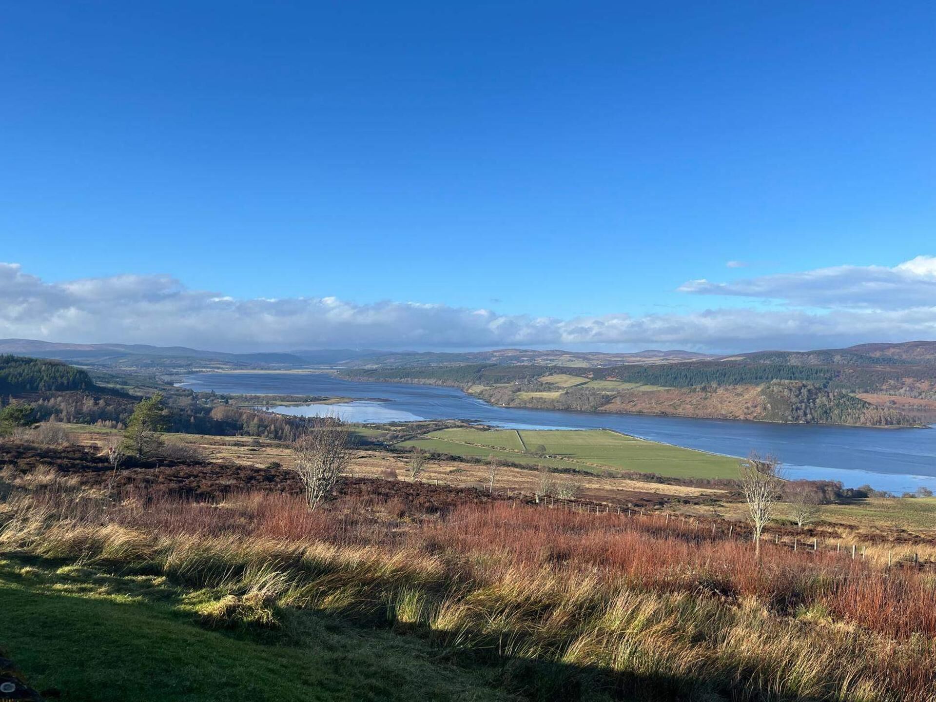 A panoramic view of a landscape with a river, hills, and a clear sky.
