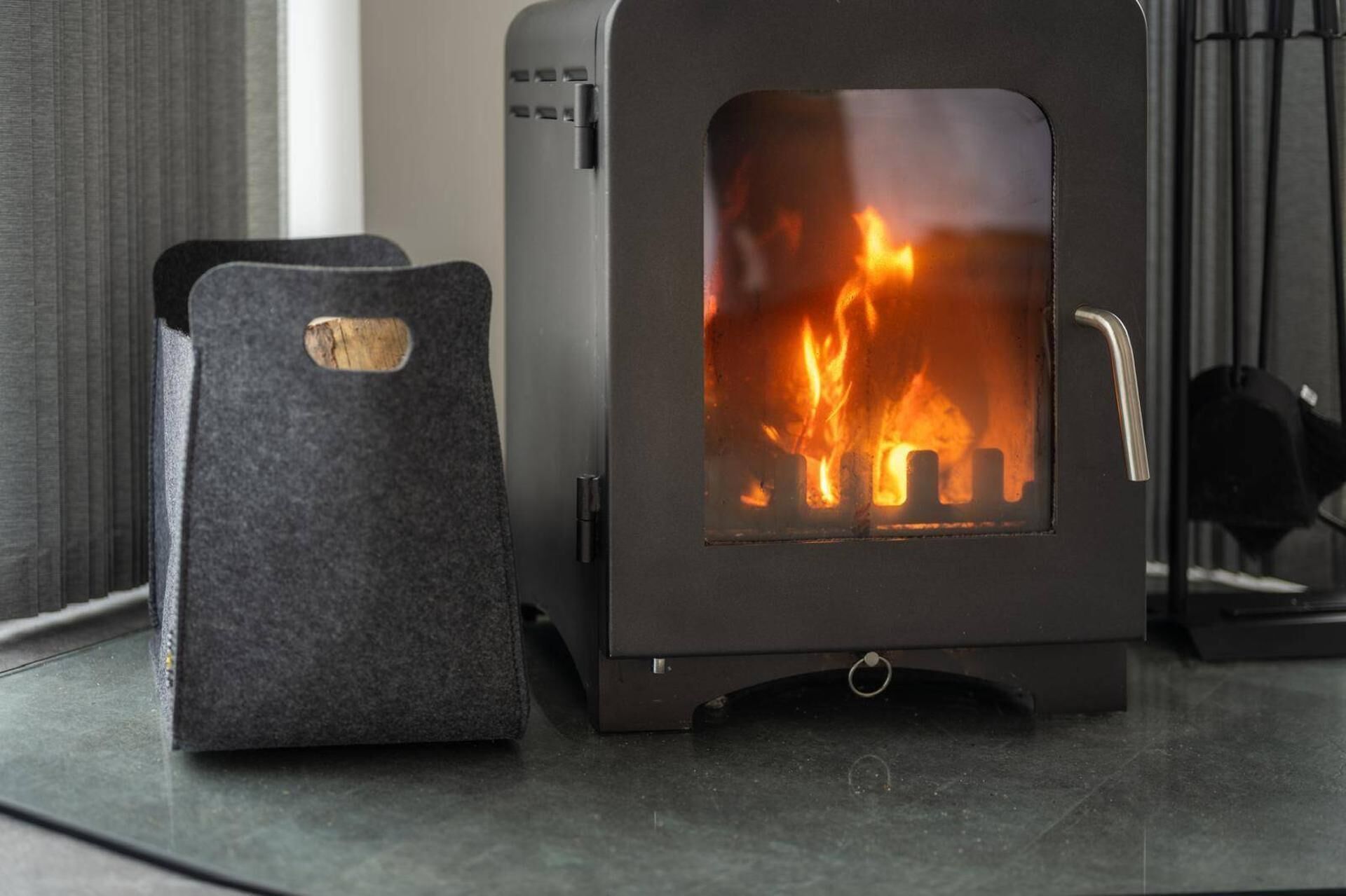 A wood-burning stove with a visible fire, a metal handle, and a small vent.