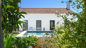 Ein modernes Haus mit Swimmingpool, großen Fenstern und einem Ziegeldach.