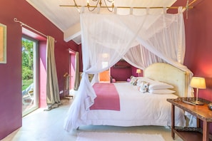 Une chambre à coucher avec un lit à baldaquin, une table de chevet avec une lampe et une vue sur l’extérieur.