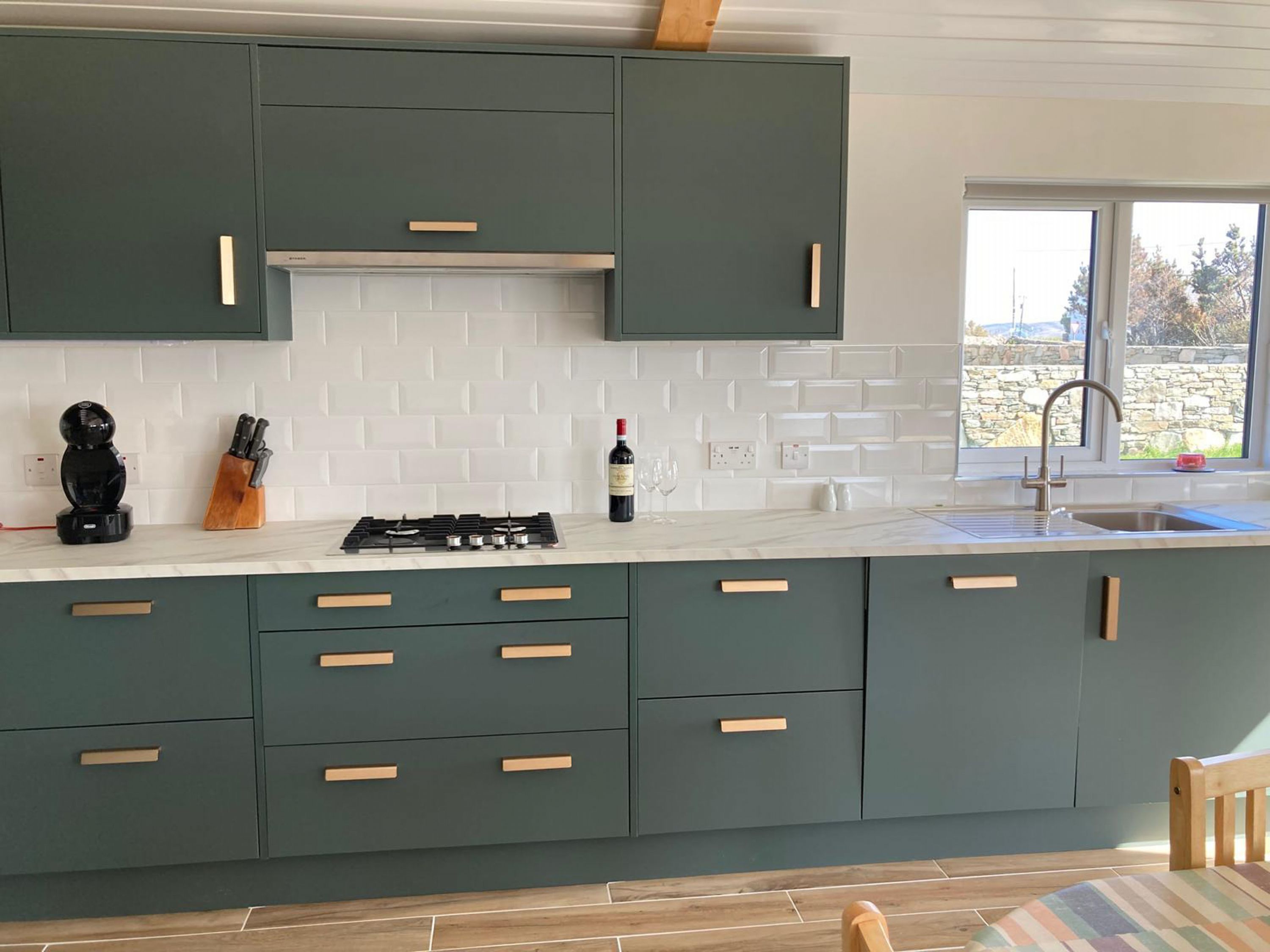 A modern kitchen with teal cabinets, white subway tiles, and a gas stove.