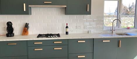 A modern kitchen with teal cabinets, white subway tiles, and a gas stove.