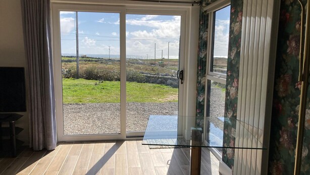 Una habitación con un amplio ventanal corredero que da a un balcón con vistas a una zona verde y un paisaje lejano.