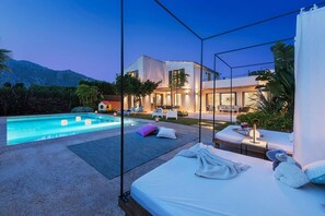A modern hotel room with a pool, outdoor seating, and a view of the mountains. - Villa 'Maronja' with Private Pool, Wi-Fi and Air Conditioning (Illes Balears)