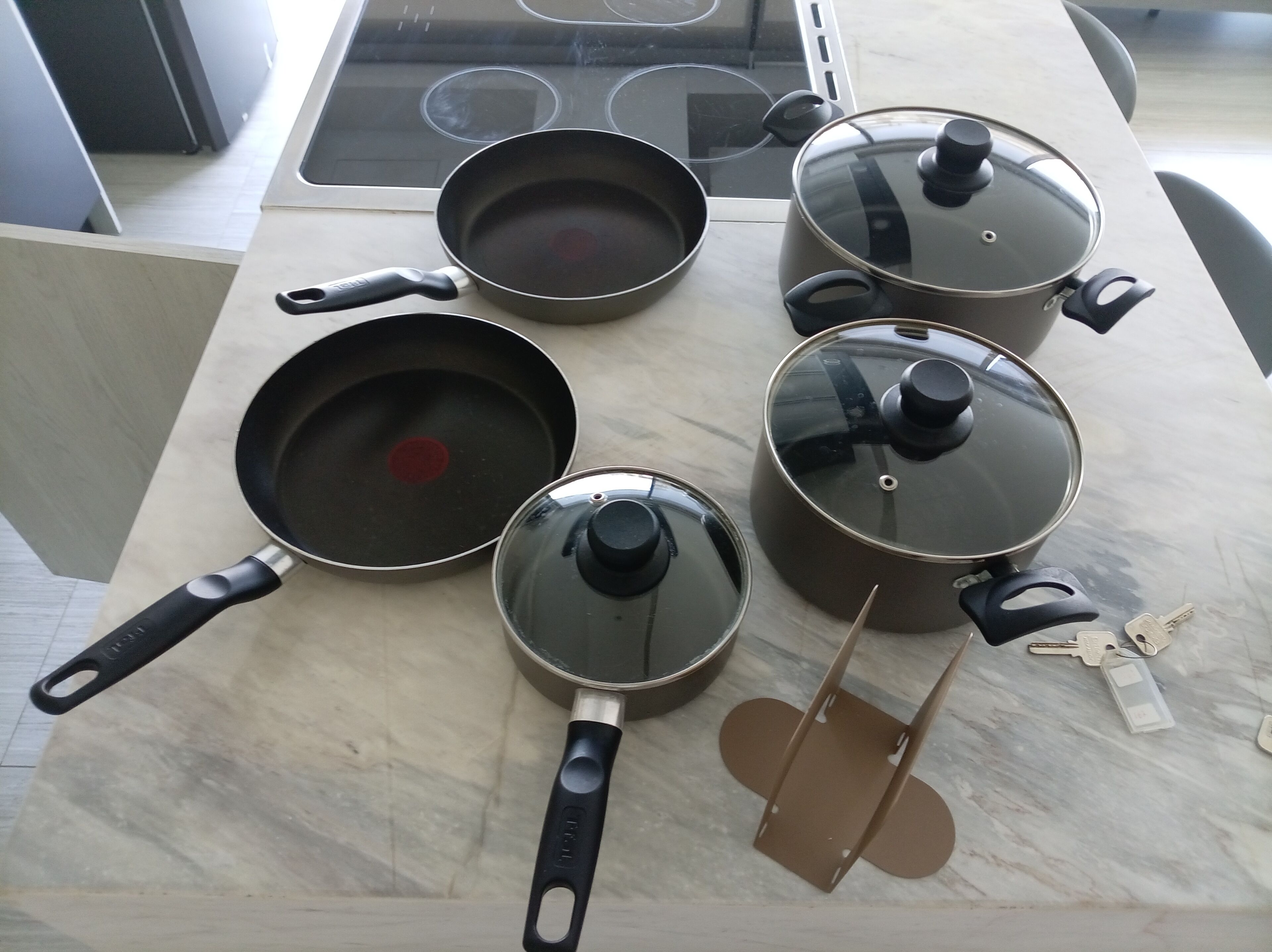 A kitchen with a stove, pots, pans, and a set of keys on the counter.