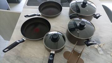 A kitchen with a stove, pots, pans, and a set of keys on the counter.
