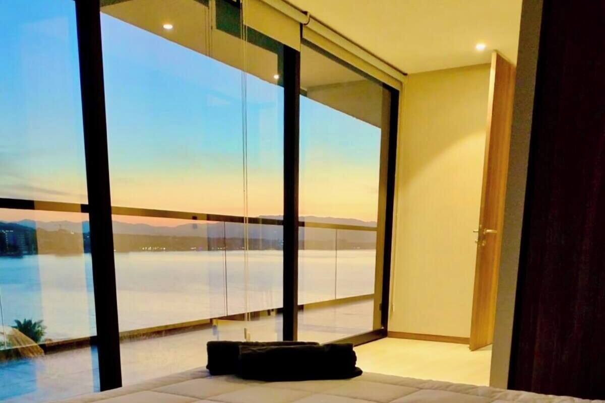 A bedroom with a large bed, a view of a snowy landscape through floor-to-ceiling windows, and a sliding door leading to an outdoor area.
