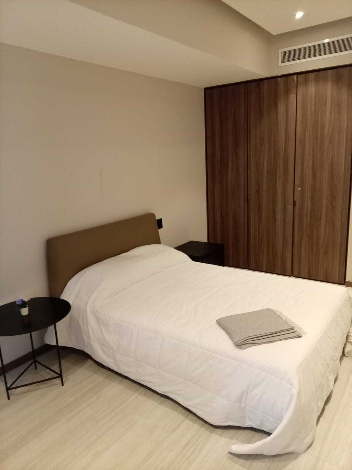 Ein Schlafzimmer mit einem Bett, einem Nachttisch, einem Kleiderschrank und einem kleinen Tisch mit einer Vase.