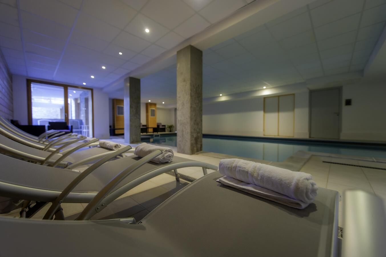 A pool area with lounge chairs and a pool.