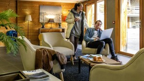 A cozy room with wooden walls, a sofa, a chair, and a table with a laptop and a plate of food. - View mountain, fitness, swimming pool, hammam, tv, ski locker, 47-52m², Vaujany (Vaujany)