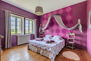 Ein Schlafzimmer mit einem Bett, einem Fenster, einer Heizung und Holzboden.