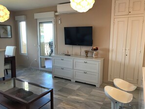 A living room with a glass coffee table, white sofa, TV, and a cabinet with drawers. - Apartment in first line of sea DENIA (Denia)