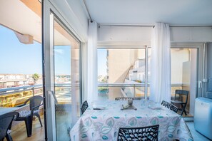 A balcony with a table set for dining, chairs, and a view of the cityscape. - Bleu Mer - Jolie T2 à la Plage (Canet-en-Roussillon)