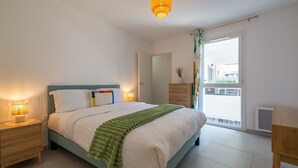 Un dormitorio con cama, lámparas de noche, cómoda, ventana con vistas y luz de techo.