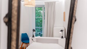A bedroom with a bed, a desk, a chair, a window with curtains, and a hanging light fixture. - Gustave - Proche centre-ville de Nantes (Nantes)