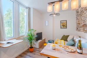A modern living room with a wooden table, a potted plant, a sofa, and a stone wall. - Gustave - Proche centre-ville de Nantes (Nantes)