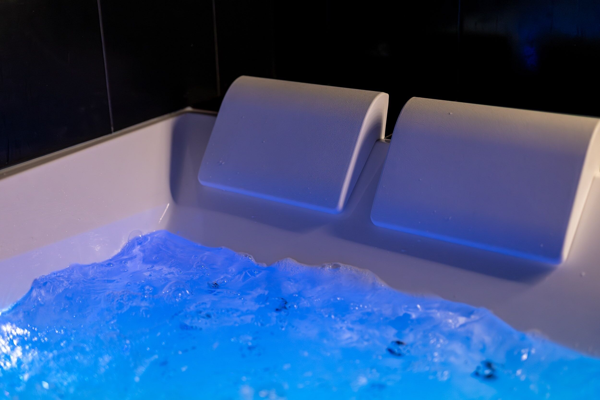 Une baignoire dotée d’un éclairage bleu et dont le niveau d’eau est visible.
