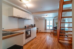 A modern kitchen with wooden flooring, white cabinetry, and a built-in oven.